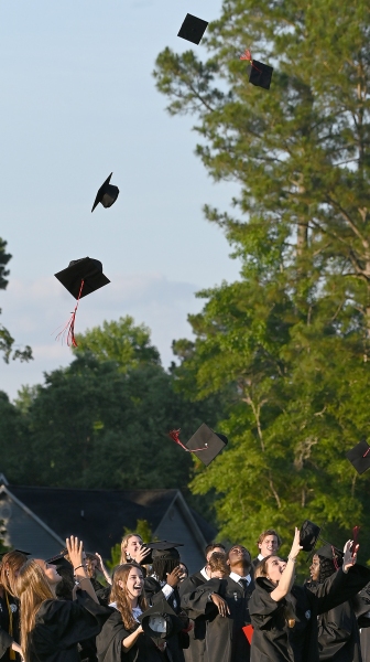 Graduates send mortarboards flying.